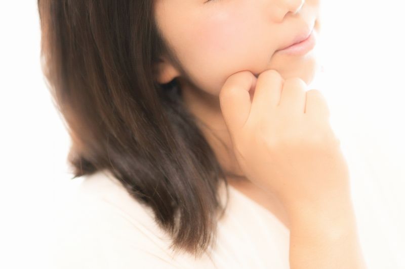 手であごのあたりを触れる女性